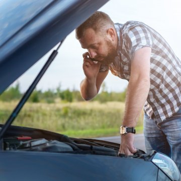 autopom! extended car warranty man on mobile phone car breakdown by the side of the road man checking under the hood 